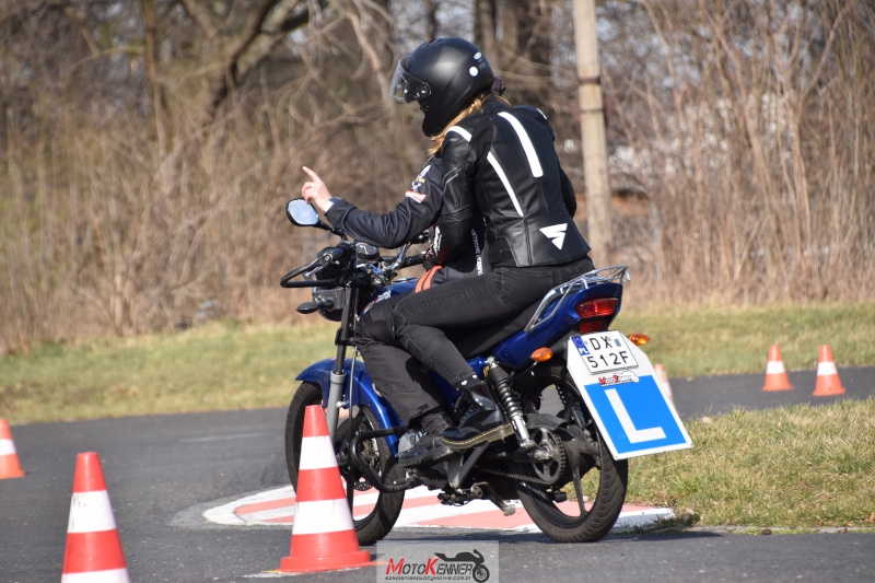 Kursantka na motocyklu z tablicą 'L' wykonująca manewr zawracania na kursie prawa jazdy A1.