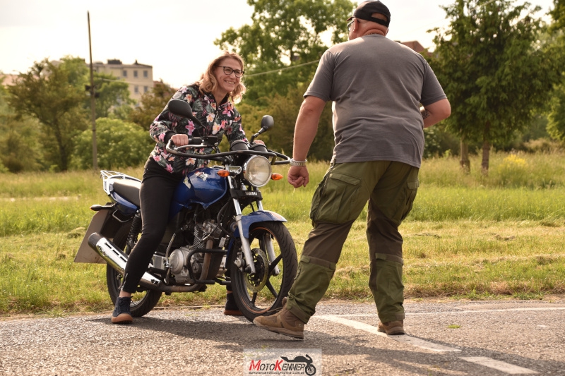 Instruktor motocyklowy udzielający wskazówek kursantce przy motocyklu podczas szkolenia na kategorię A1.