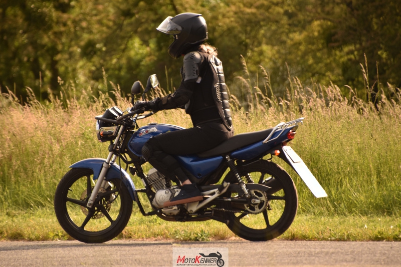 Kursantka na motocyklu z tabliczką 'L' ćwicząca manewrowanie między pachołkami na kursie na prawo jazdy A1.