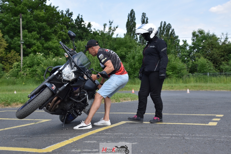 Instruktor motocyklowy pomaga kursantce podnieść motocykl podczas szkolenia na kategorię A2.