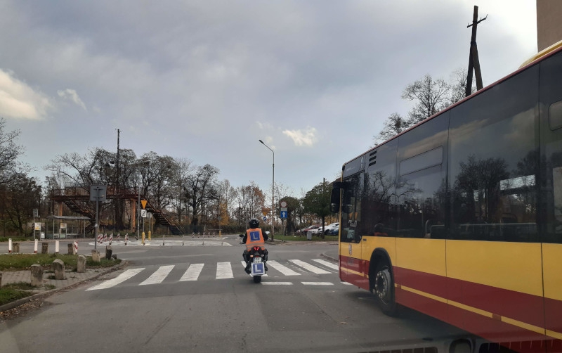 Zdjęcie przedstawiające kursanta prawy jazdy na kategorię AM jadącego obok żółtego autobusu w Wrocławiu