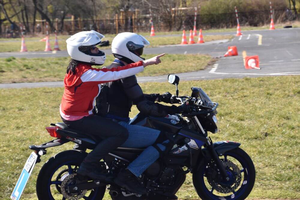 Instruktor motocyklowy prowadzi szkolenie praktyczne z kursantem na motocyklu podczas kursu na prawo jazdy kategorii A.