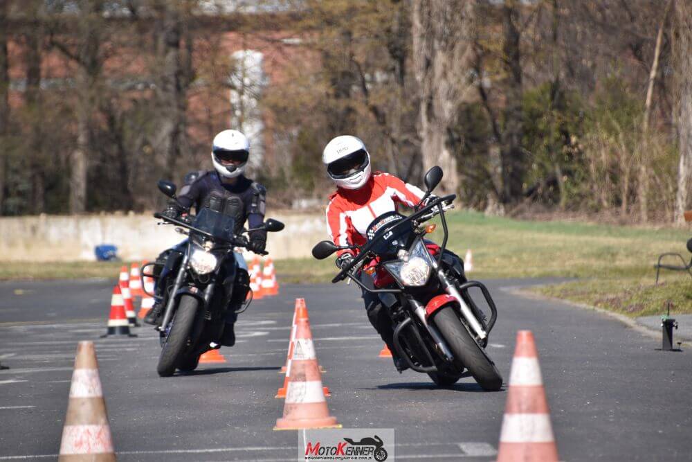 Kurs motocyklowy na prawo jazdy kategorii A z kursantami ćwiczącymi manewry wokół pachołków.